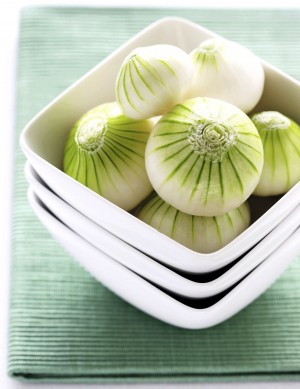 Peeled white onions in bowl, close-up